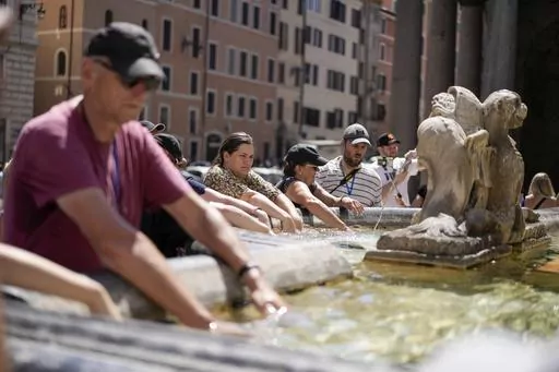 People cool off at a fountain in front of the Pantheon, in Rome, Saturday, Aug. 19, 2023, where temperatures were expected to reach as high as 37 Celsius (98 Farenheit). This was the hottest summer on record across the globe, forcing many tourists to rethink how and where they travel. (AP Photo/Andrew Medichini, FIle)