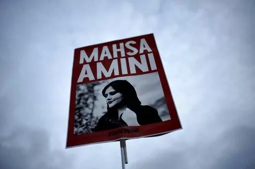 A woman holds a placard with a picture of Iranian woman Mahsa Amini during a protest against her death, in Berlin, Germany, Wednesday, Sept. 28, 2022.  Iranian celebrities have been startlingly public in their support for the massive anti-government protests shaking their country. And the ruling establishment is lashing back. Celebrities have found themselves targeted for arrest, have had passports confiscated and faced other harassment. (AP Photo/Markus Schreiber, File)