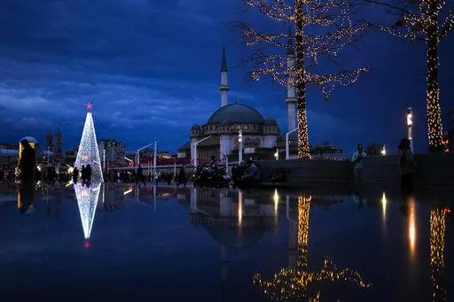 Pedestrians walk past a Christmas tree next to Taksim mosque at Taksim square in Istanbul, Turkey, Friday, Dec. 10, 2021. (AP Photo/Francisco Seco)