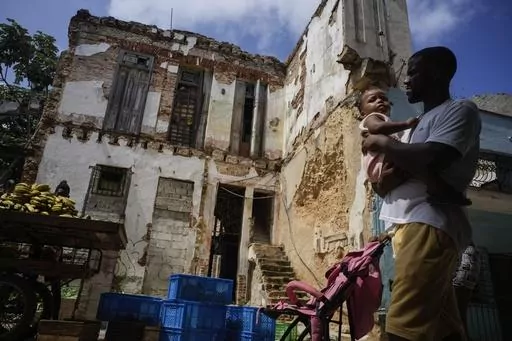 Residents walk past dilapidated mansion on Villegas Street in Havana, Cuba, Thursday, Oct. 5, 2023. The two-story building, which houses six families, is one of many, once luxurious houses that in recent years have partially collapsed or suffered visible damage. (AP Photo/Ramon Espinosa)