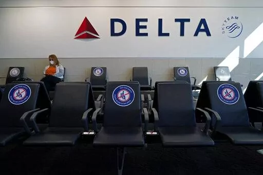 A passenger wears a face mask as she waits in a socially-distance area for a Delta Airlines flight, Wednesday, Feb. 3, 2021, at Hartsfield-Jackson International Airport in Atlanta.  Delta Air Lines will start paying flight attendants during the time that passengers are boarding. That's a first for a major U.S. airline. Flight attendants in the U.S. generally don't begin getting paid until the doors close after boarding. Delta said Tuesday, April 26, 2022, that the change will take effect in June