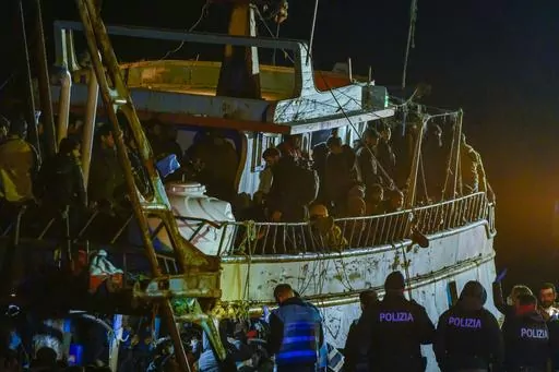 Police check a fishing boat with some 500 migrants in the southern Italian port of Crotone, early Saturday, March 11, 2023. The Italian coast guard was responding to three smugglers boats carrying more than 1,300 migrants “in danger” off Italy’s southern coast, officials said Friday. Three small coast guard boats were rescuing a boat with 500 migrants about 700 miles off the Calabria region, which forms the toe of the Italian boot. (AP Photo/Valeria Ferraro)