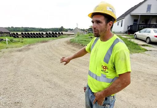 Taylor Purdy, a pipe layer with Complete General Construction, answers questions about his experience working around the new Intel semiconductor manufacturing plant construction site in Johnstown, Ohio, during an interview near the site Friday, Aug. 5, 2022. Purdy spends his days in trenches helping position storm and sanitary sewers and waterlines. Overtime is plentiful as deadlines approach. (AP Photo/Paul Vernon)