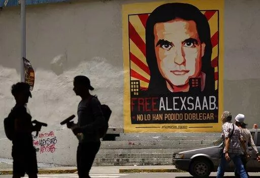 In this Sept. 9, 2021 file photo, pedestrians walk near a poster of Alex Saab that reads in Spanish "Alex Saab Free. They haven't been able to bend him," in Caracas, Venezuela. Newly unsealed court records show that the Colombian businessman linked to Venezuelan President Nicolas Maduro was secretly signed up by the D.E.A. as a cooperating source in 2018 and gave agents information about bribes he paid to Venezuelan officials. However, he was deactivated as a source after failing to meet a deadl