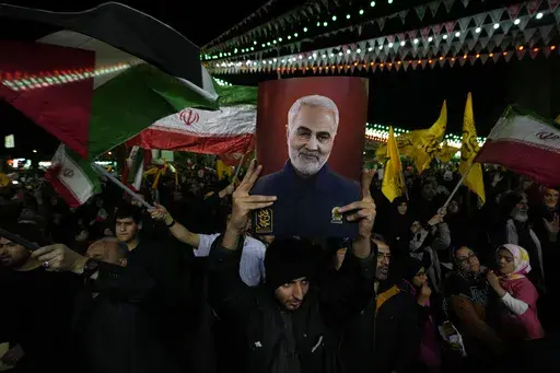 Iranian protesters wave Iranian and Palestinian flags as one of them holds up a poster of the late Iranian Revolutionary Guard Gen. Qassem Soleimani, who was killed in a U.S. drone attack in 2020, during their anti-Israeli gathering to condemn killing members of the Iranian Revolutionary Guards in Syria, at the Felestin (Palestine) Sq. in downtown Tehran, Iran, Monday, April 1, 2024. An Israeli airstrike that demolished Iran's consulate in Syria killed two Iranian generals and five officers, Syr