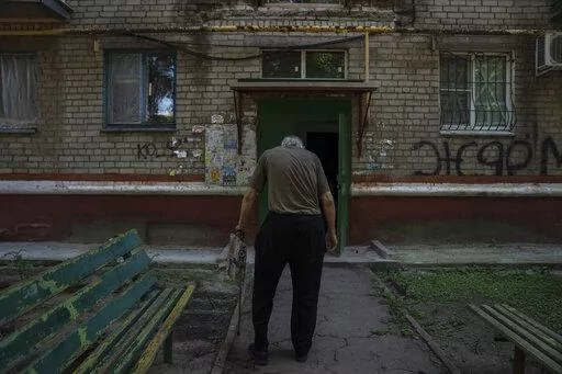Seventy-year-old pensioner Valerii Ilchenko, who lives alone and is refusing to evacuate, walks to his apartment, after filling out his daily crossword, in Kramatorsk, eastern Ukraine, Wednesday, July 6, 2022. Now a widower, Ilchenko says he still has no intention of leaving. "I don't have anywhere to go and don't want to either. What would I do there? Here at least I can sit on the bench, I can watch TV," he says in an interview in his single-room apartment. (AP Photo/Nariman El-Mofty)
