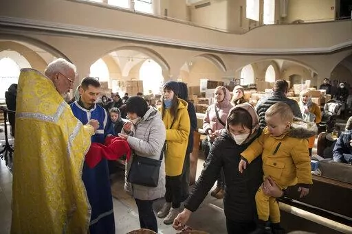 Members of the Ukrainian Orthodox community, who have found shelter for their church service in an evangelical church, and refugees from Ukraine celebrate a church service and pray for peace in Berlin, Sunday, March 20, 2022. (AP Photo/Steffi Loos)