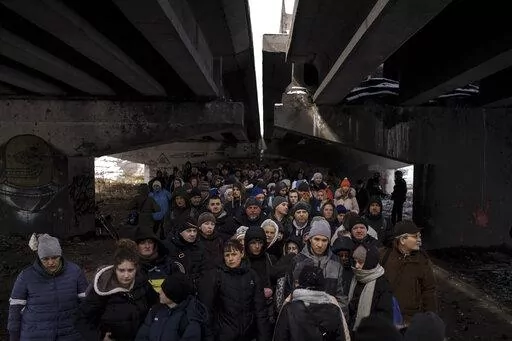 People crowd under a destroyed bridge as they try to flee, crossing the Irpin river on the outskirts of Kyiv, Ukraine, Tuesday, March 8, 2022. Russia's relentless digital assaults on Ukraine may have caused less damage than many anticipated. But most of its hacking is focused on a different goal that gets less attention but has chilling potential consequences: data collection. (AP Photo/Felipe Dana, File)