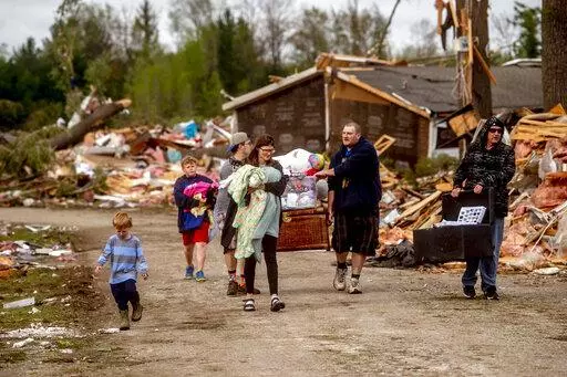 Resident Stephanie Kerwin, center, holds her baby Octavius in one arm and dog Pixie in the other as she and her family carry what they could salvage from her home in Nottingham Forest Mobile Home Park, Saturday, May 21, 2022, in Gaylord, Mich., following a tornado the day before. "This morning is when it first hit me...I could have lost people that I really love. I am so grateful," Kerwin said. (Jake May/MLive.com/The Flint Journal via AP)