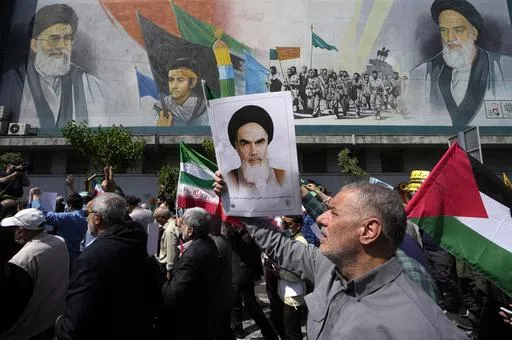 Iranian worshippers walk past a mural showing the late revolutionary founder Ayatollah Khomeini, right, Supreme Leader Ayatollah Ali Khamenei, left, and Basij paramilitary force, as they hold posters of Ayatollah Khomeini and Iranian and Palestinian flags in an anti-Israeli gathering after Friday prayers in Tehran, Iran, April 19, 2024. This month's unprecedented direct attacks between Iran and Israel are revealing deeper insights into both militaries. Experts say Friday's apparent precision str