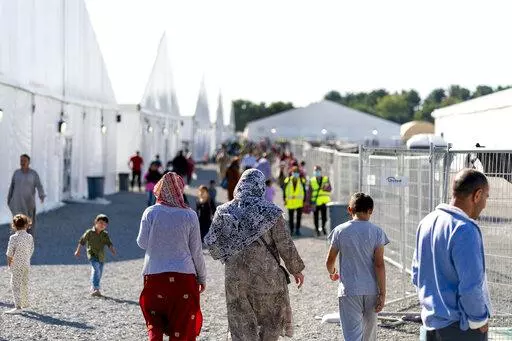 Afghan refugees walk through an Afghan refugee camp at Joint Base McGuire Dix Lakehurst, N.J., on Sept. 27, 2021. Thousands of refugees who fled Afghanistan and now live in the United States are facing an uncertain future. Congress has failed so far to create a pathway to residency for Afghans who came to America after working alongside U.S. soldiers in the war. (AP Photo/Andrew Harnik, File)