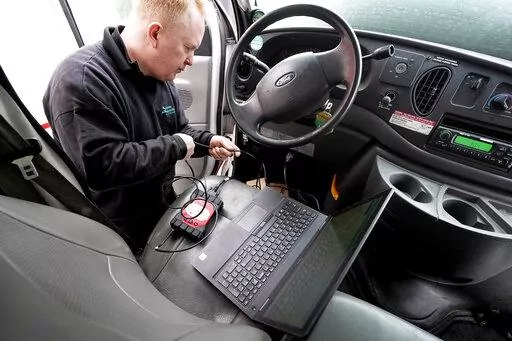 Brian Hohmann, mechanic and owner of Accurate Automotive, in Burlington, Mass., attaches a diagnostics scan tool, center left, to a vehicle and a laptop computer, below, Tuesday, Feb. 1, 2022, in Burlington. The diagnostics scan tool sends information from the vehicle's computer to the laptop so a mechanic can view information about the vehicle's performance. Hohmann said most independent shops are perfectly capable of competing with dealerships on both repair skills and price as long as they ha
