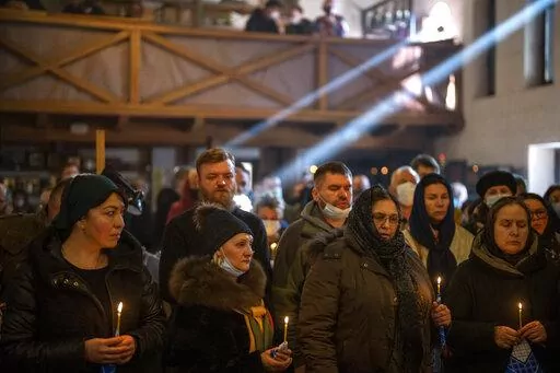 People pray next to the body of Ukrainian Army captain Anton Sydorov, 35, killed in eastern Ukraine, during his funeral in Kyiv, Ukraine, Tuesday, Feb. 22, 2022. (AP Photo/Emilio Morenatti, File)
